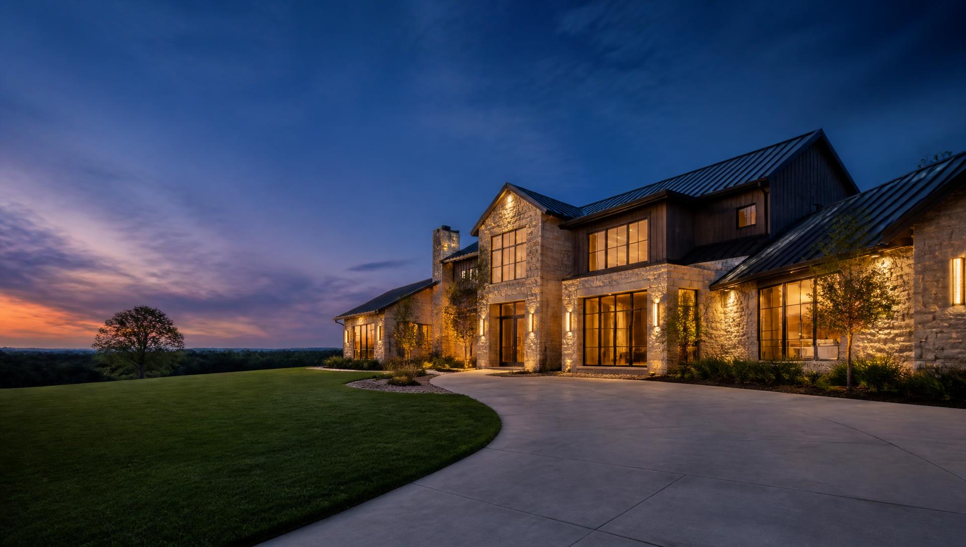 A luxury custom home at dusk in Dallas–Fort Worth with warm interior lighting and manicured landscaping.